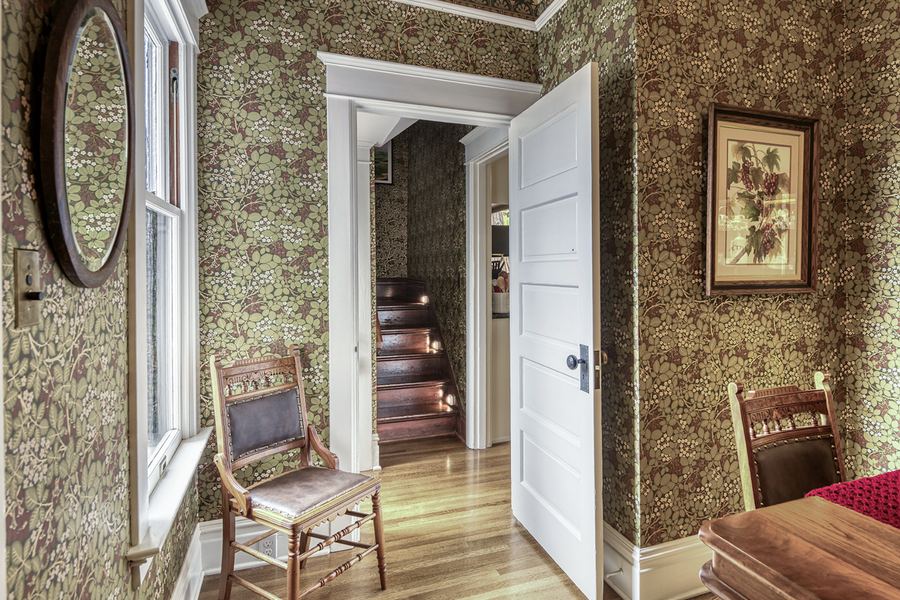 A papered back hall with a narrow wooden stair