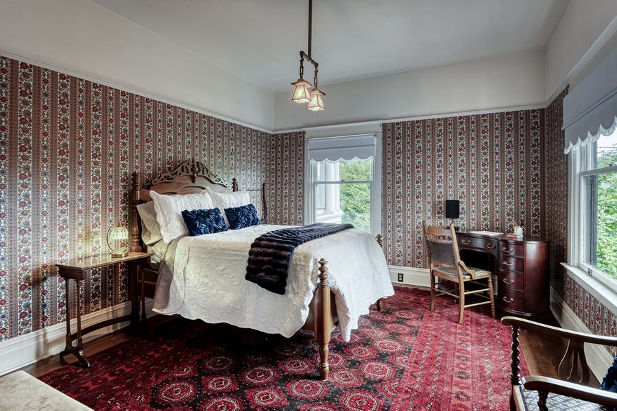 The Barnwell Suite: red striped wallpaper, a carved bed and a red rug
