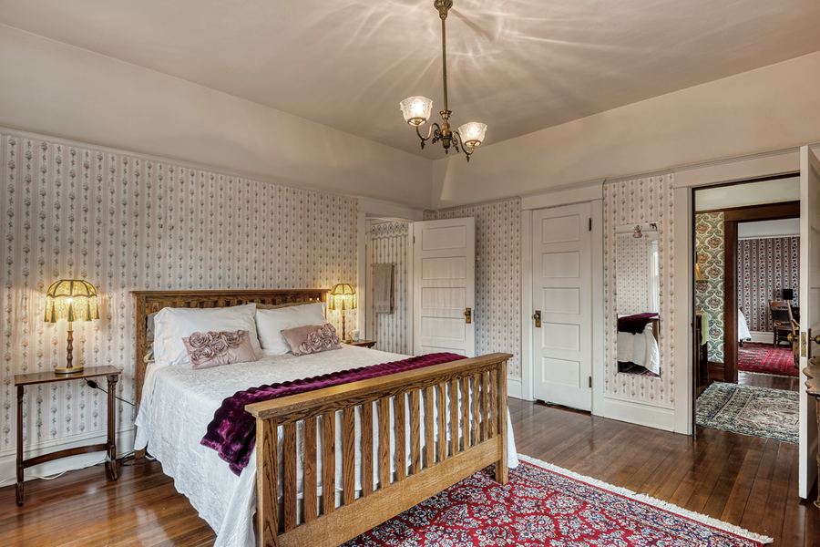 The Briehl Suite: rose wallpaper, an oak bed and a brass chandelier