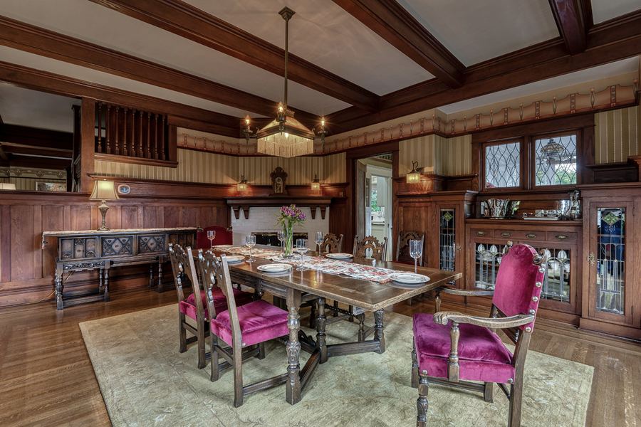 The dining room: beamed ceiling, leaded-glass built-ins and crimson chairs