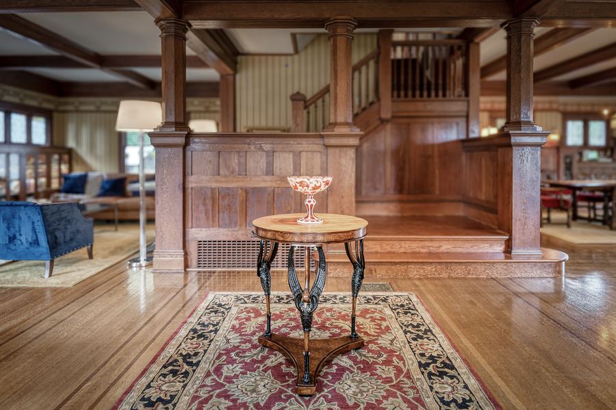 The entry hall: oak panelling, the carved staircase and a pedestal table