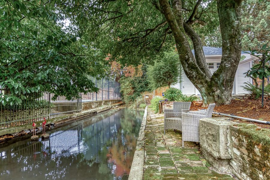 A canal running along the side garden, with outdoor chairs under the trees