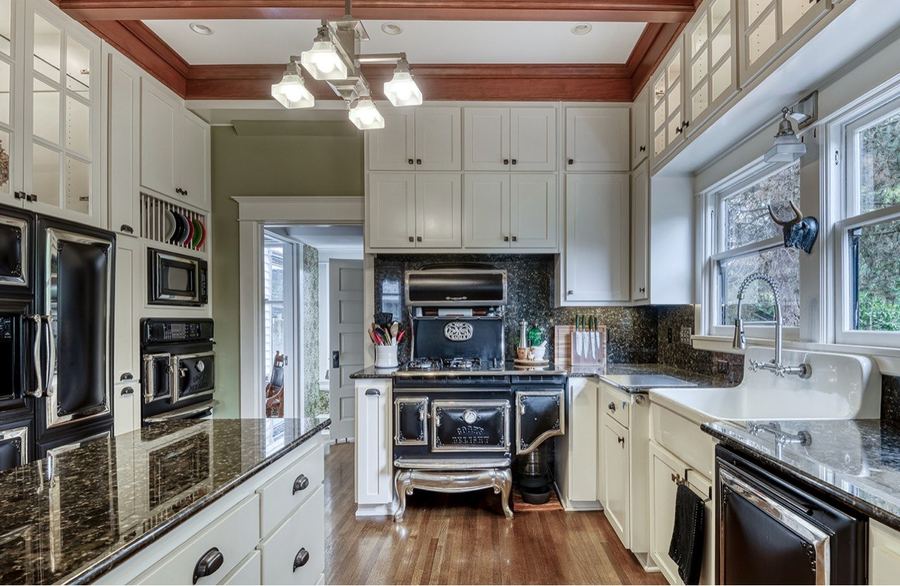 The kitchen: a vintage-style range, a farmhouse sink, white cabinets and granite counters
