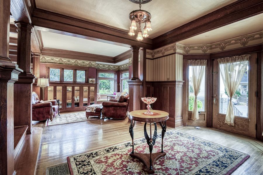 The entry hall looking toward the front doors, with beamed ceilings and a period chandelier
