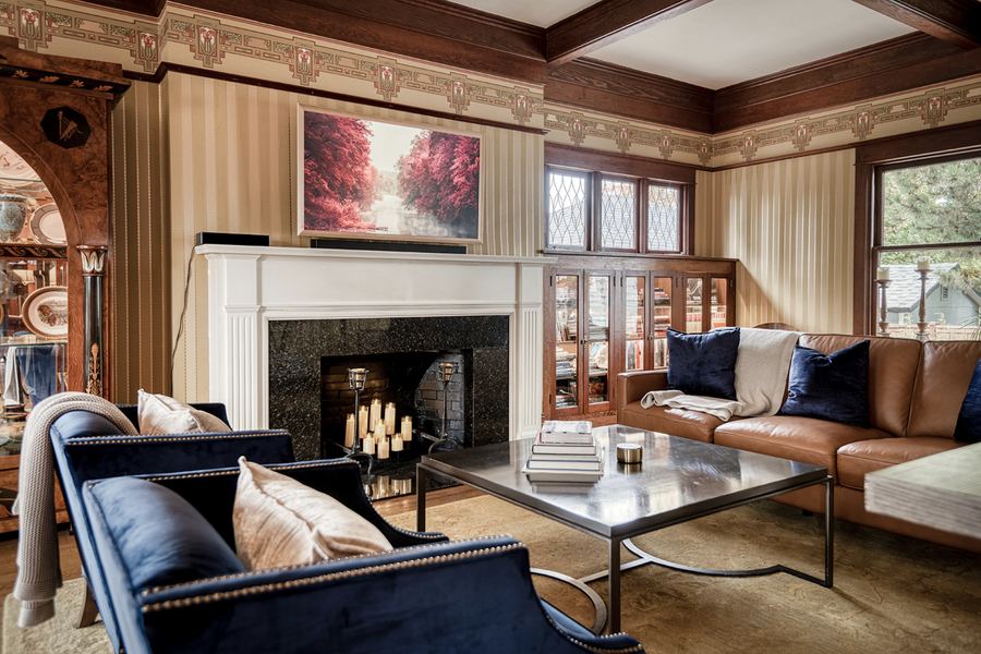 A sitting room with a tiled fireplace, leather and velvet sofas