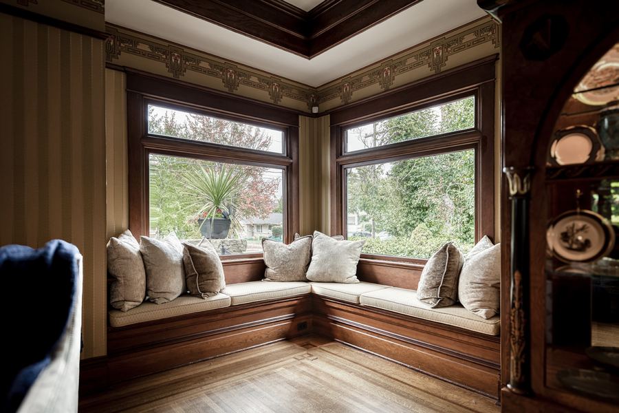 A corner window seat with cream cushions, off the entry hall