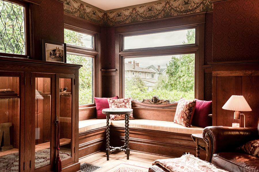 The study: a bay window seat with crimson cushions and wood panelling